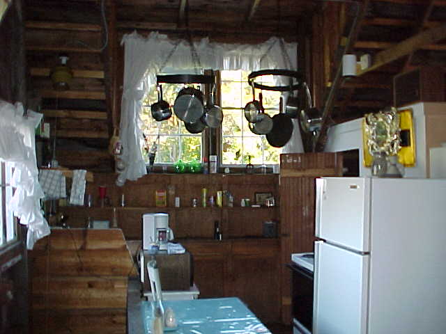 Kitchenette with sink, stove, refrigerator with ice maker; bathroom with shower in the background